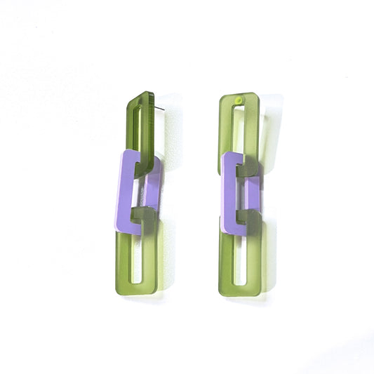 Closeup of large acrylic chain link earrings in translucent olive green and opaque lavender by Barbe Saint John.