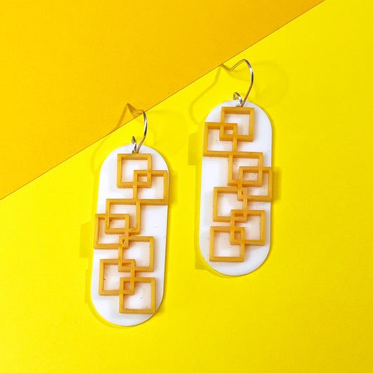 Closeup of tangerine square grid earrings in orange and white from by Barbe Jewelry. 