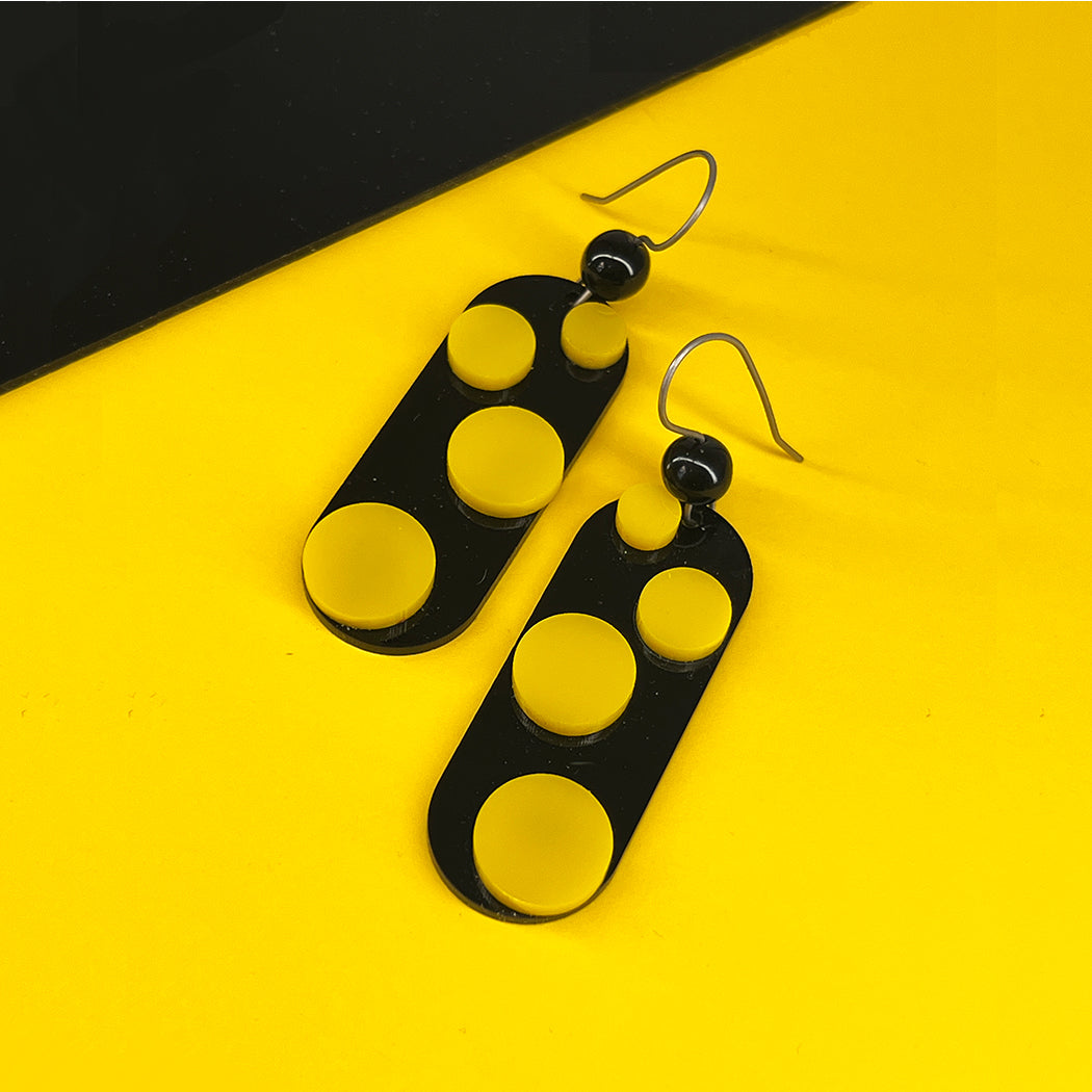 Infinite Dot Love Earrings in black and yellow on black and yellow background from by Barbe Jewelry
